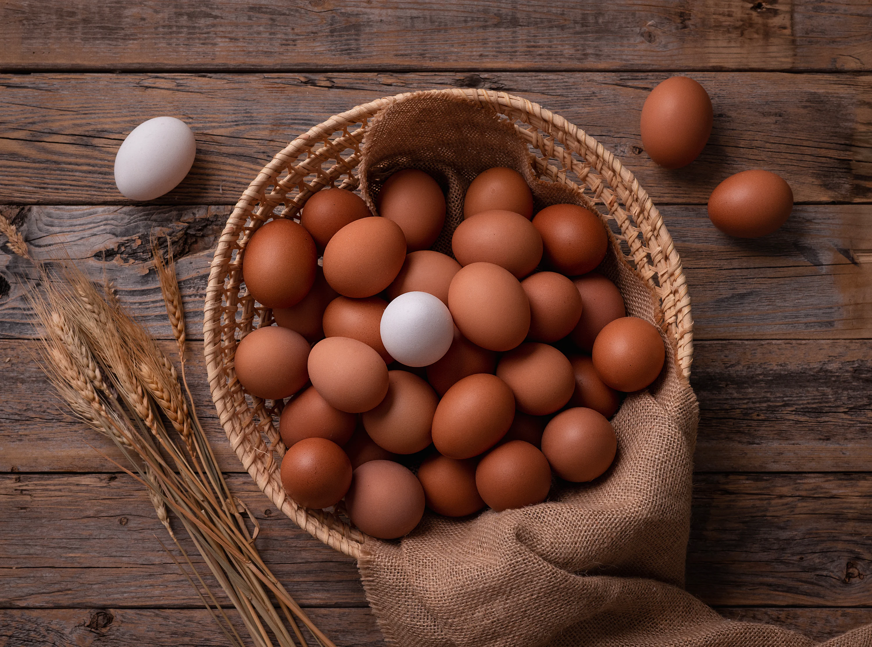 a basket filled with brown and white eggs on top of a wooden table
