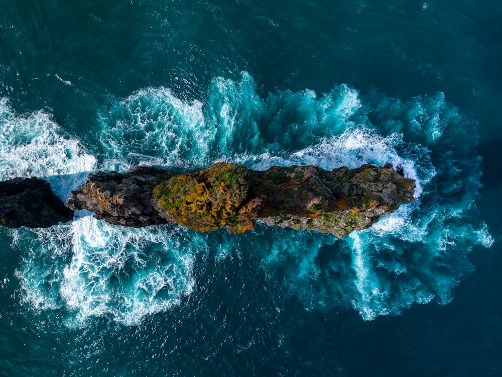 an aerial view of a rock formation in the middle of the ocean