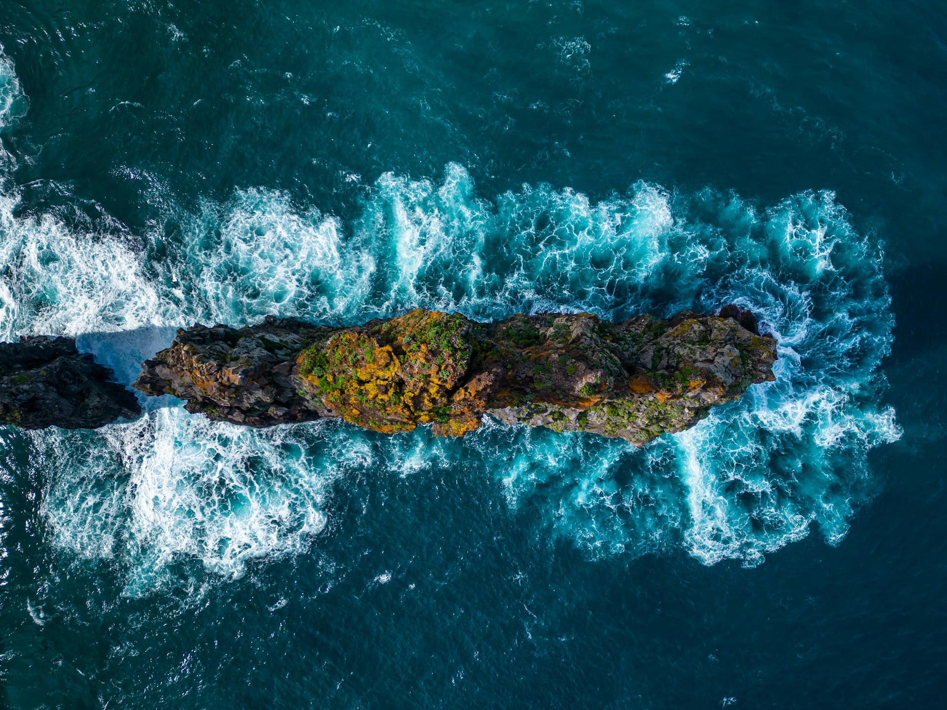 an aerial view of a rock formation in the middle of the ocean
