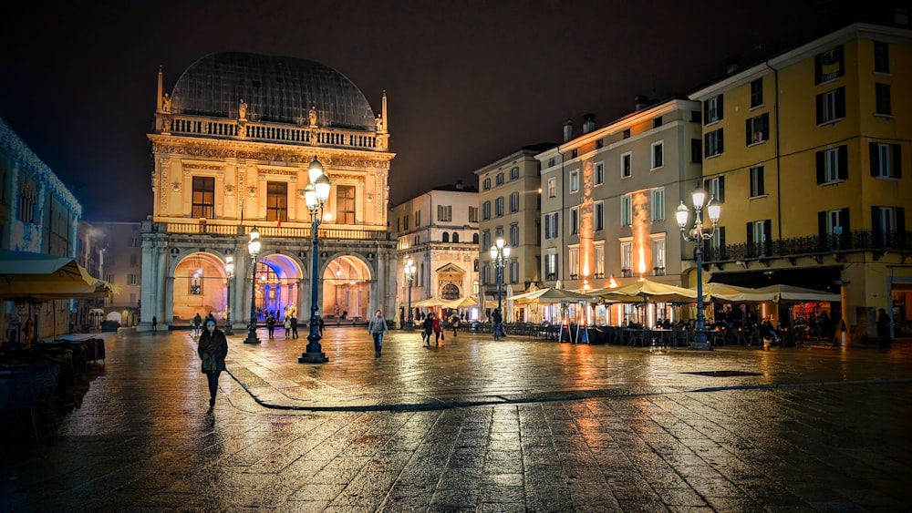 Una plaza de la ciudad por la noche con gente caminando por los alrededores