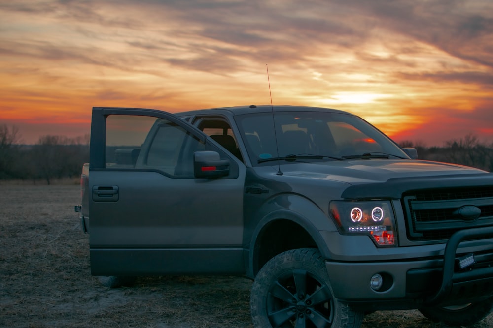 a pickup truck parked in a field at sunset