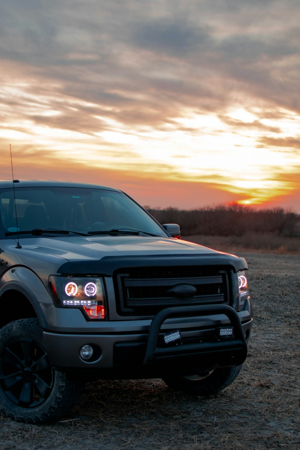 a truck parked in a field with a sunset in the background