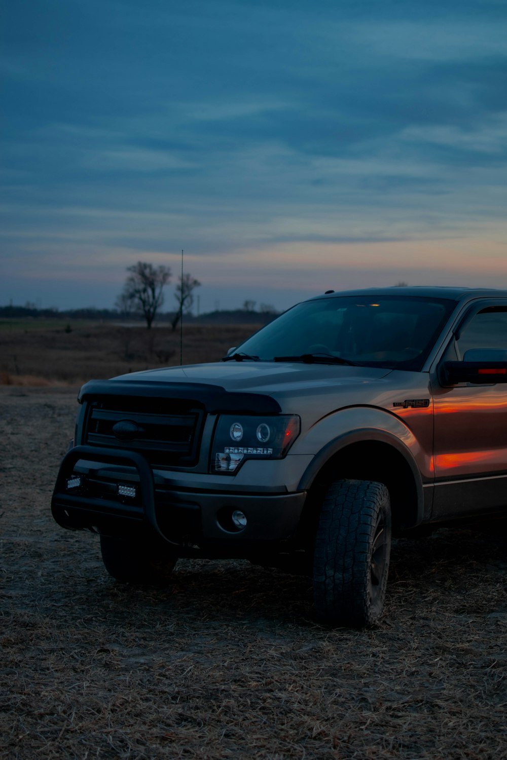 a pickup truck parked in a field at sunset