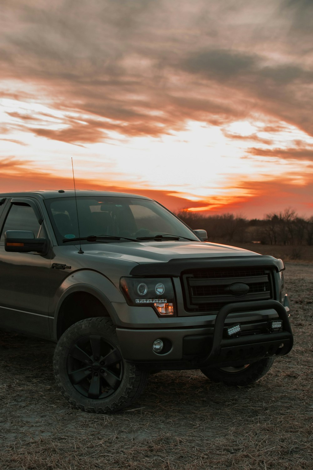 a truck parked in a field with a sunset in the background