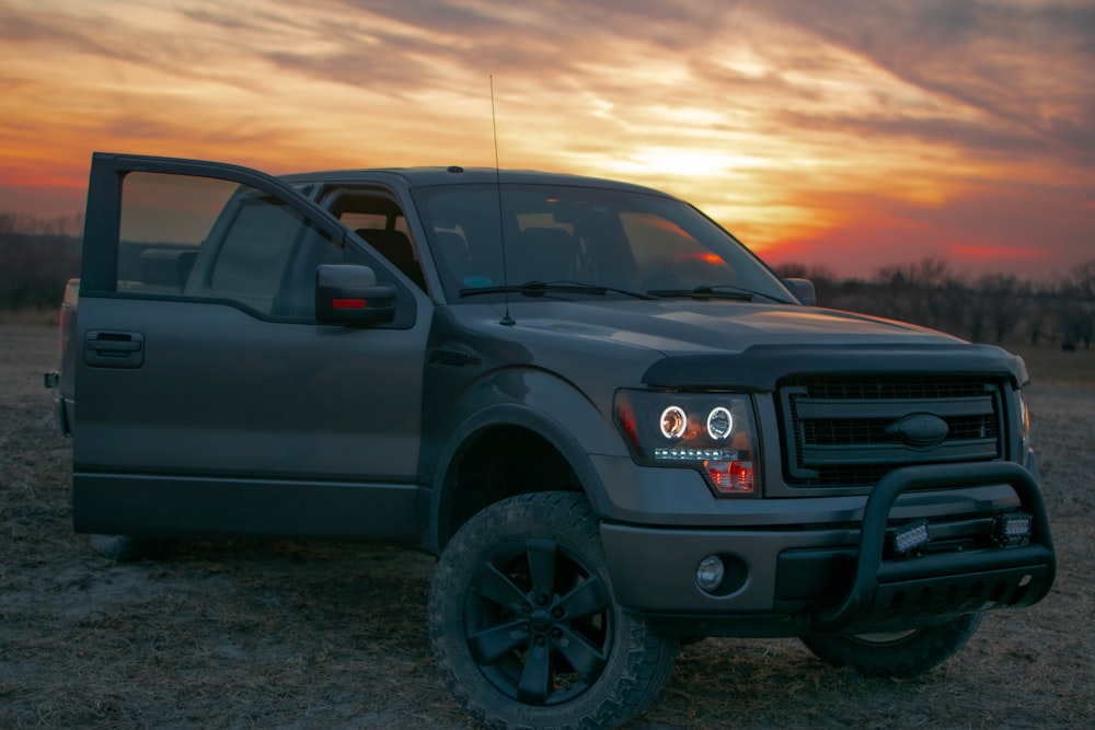 a pickup truck parked in a field at sunset