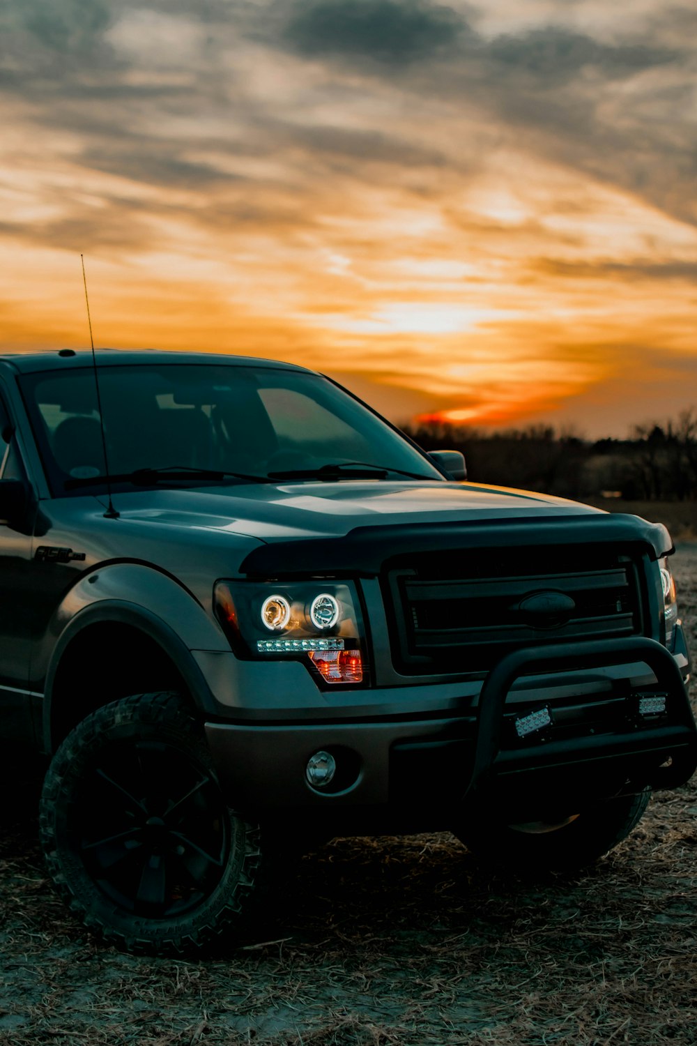 a pickup truck parked in a field at sunset