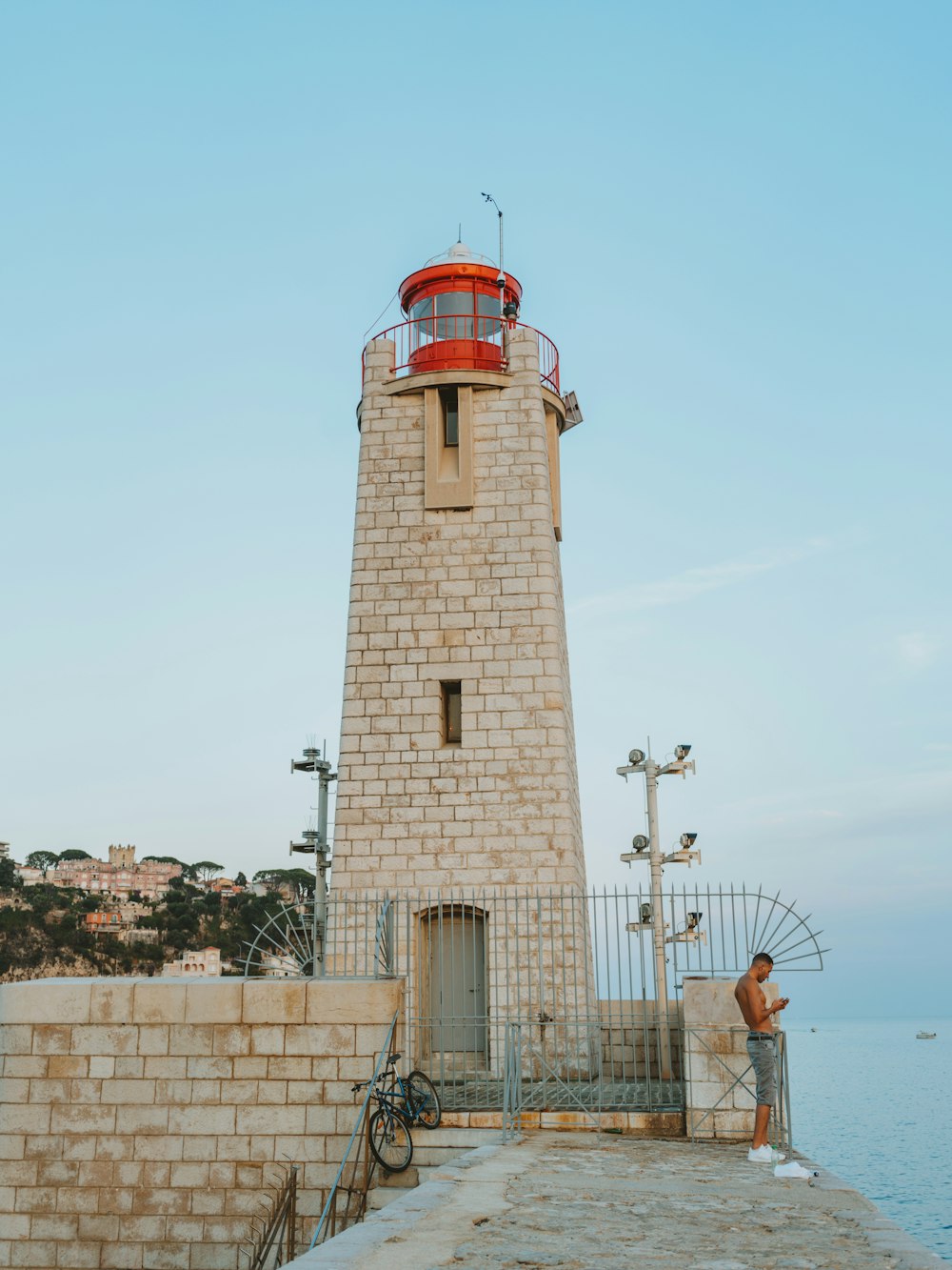 a man standing next to a light house near the ocean