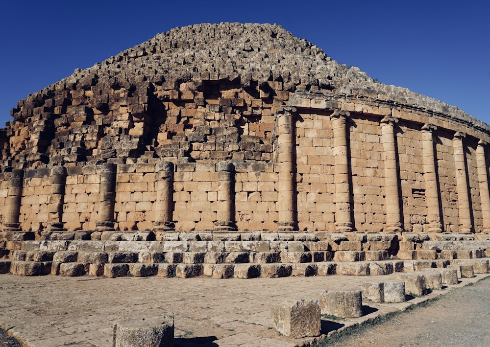 a large building made of bricks sitting on top of a dirt field