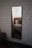 Elegant custom-cut mirror reflecting a cozy, stylish bedroom interior with soft lighting.