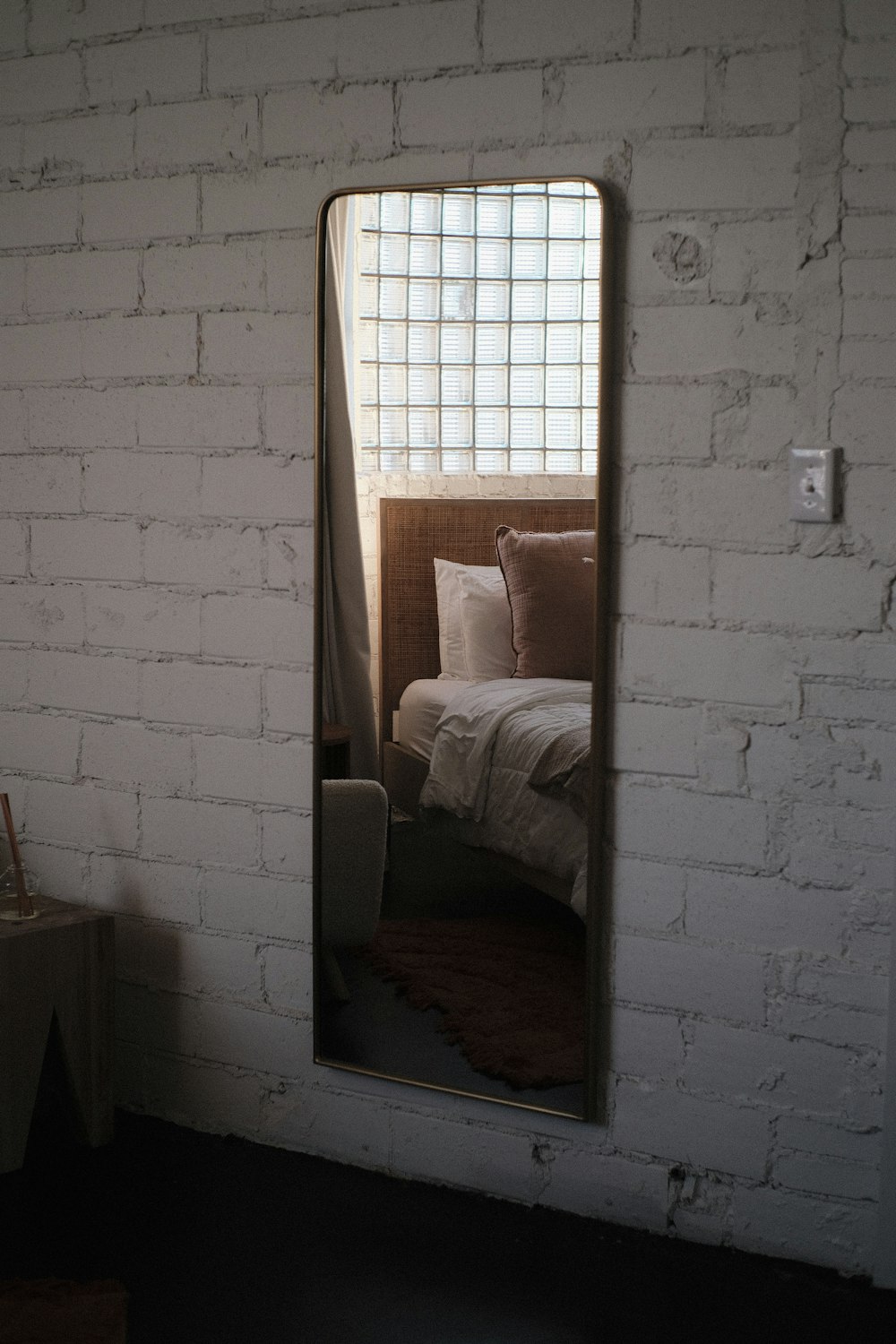 a white brick wall with a mirror reflecting a bed
