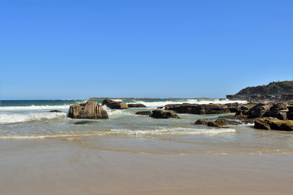 a sandy beach with waves coming in and out of the water