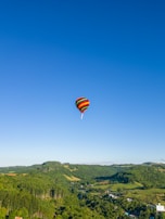 A colorful hot air balloon floating over a patchwork of green fields.