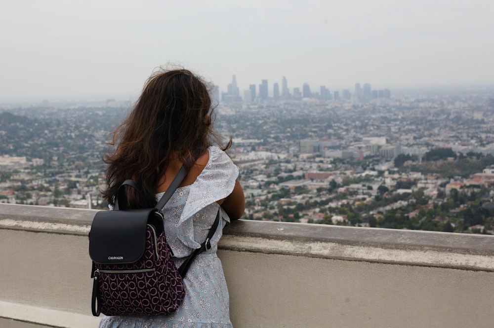a woman with a backpack looking out over a city