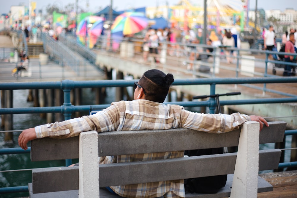 a person sitting on a bench in front of a pier