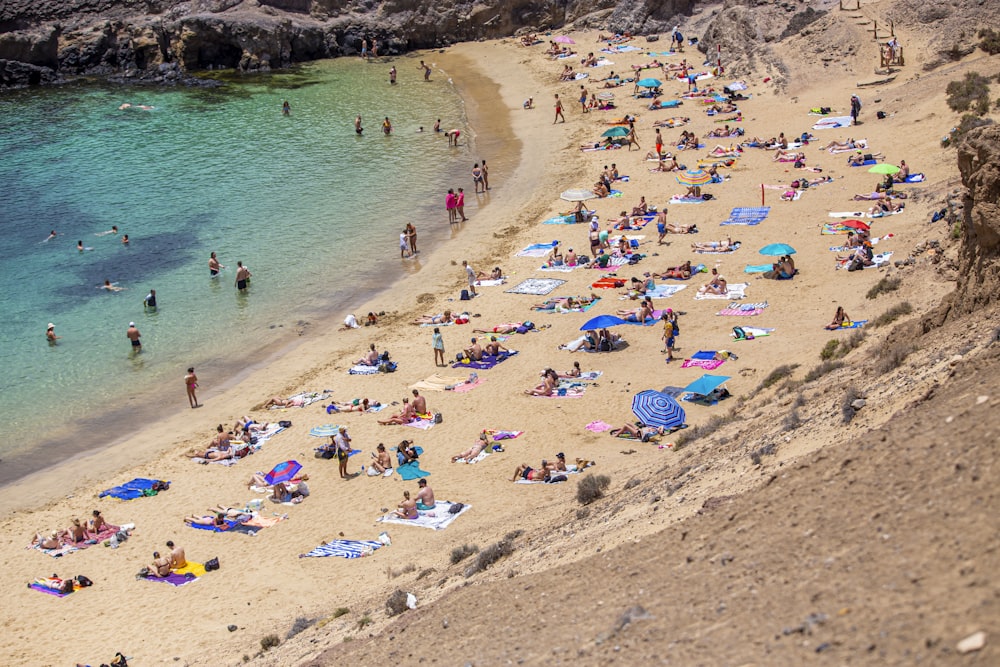 a crowded beach with people and umbrellas on a sunny day