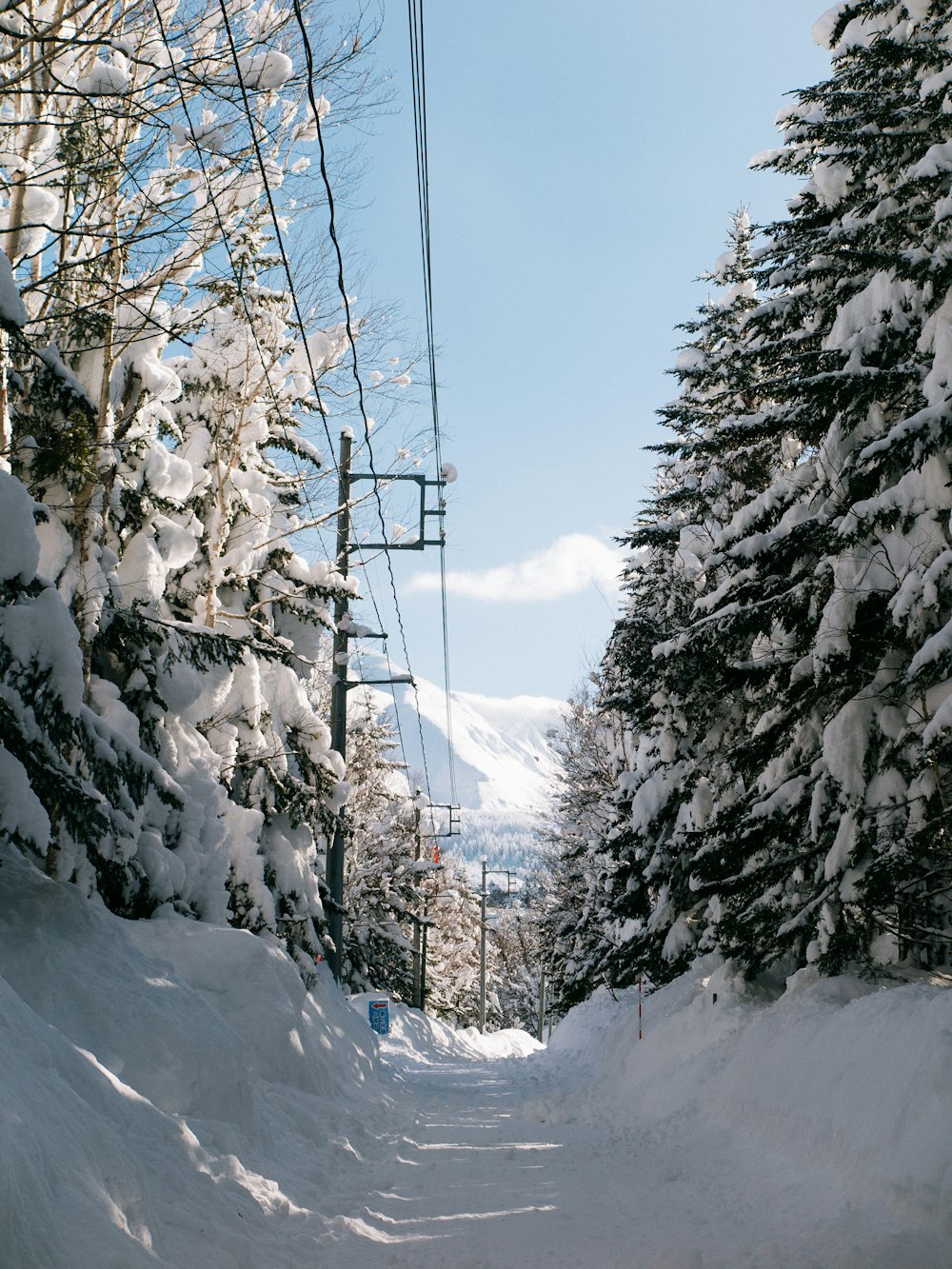 a snow covered road with a ski lift in the background