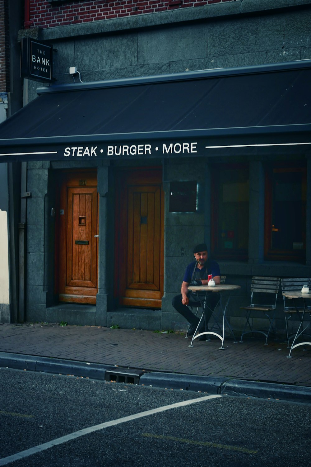 a man sitting at a table outside of a restaurant