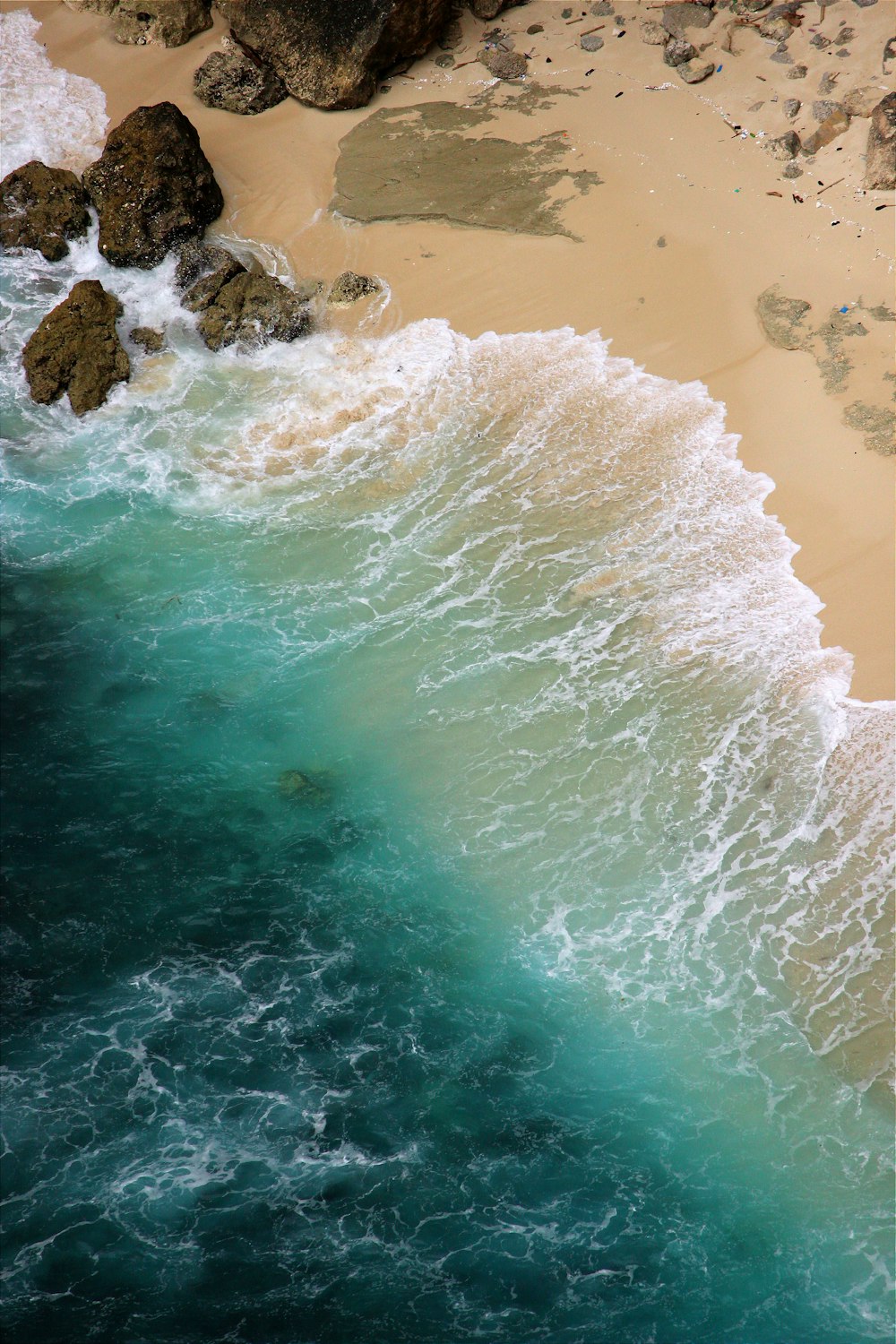 an aerial view of a beach with waves crashing on the shore