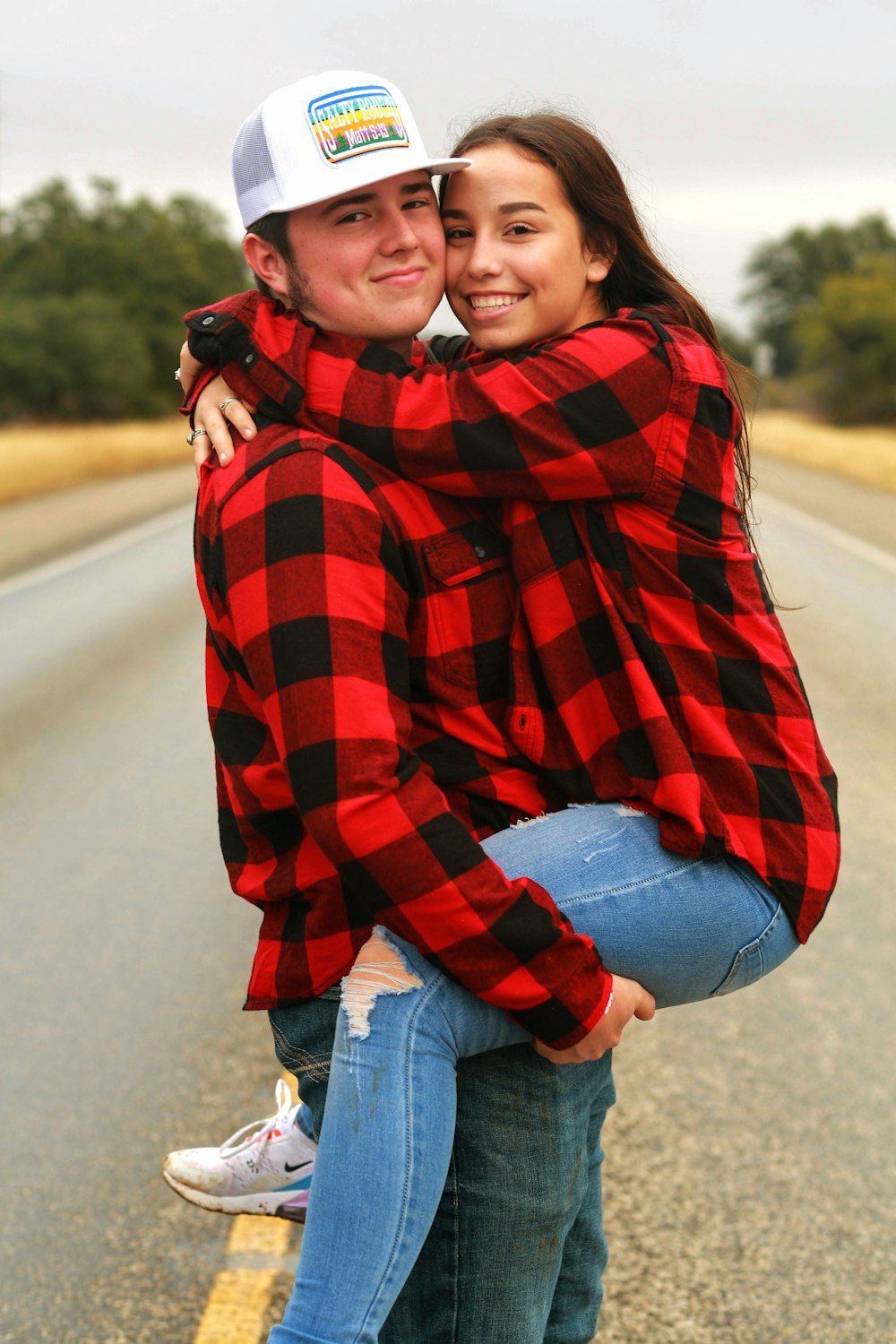 a man and woman hugging on the side of the road