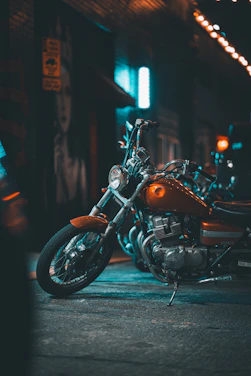 A vibrant photo capturing a classic Indian motorcycle gleaming under city lights with riders gearing up in neon-accented gear.