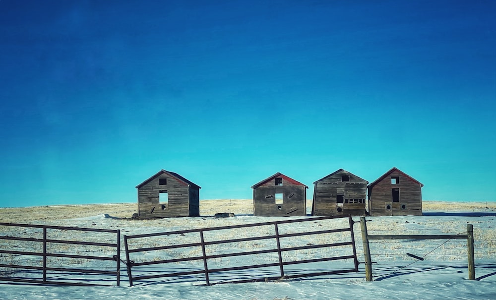 three wooden buildings sitting on top of a snow covered field