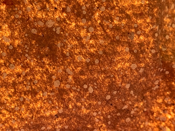 Close-up of adhesive being applied with a glue gun on flooring material in warm orange and green tones.