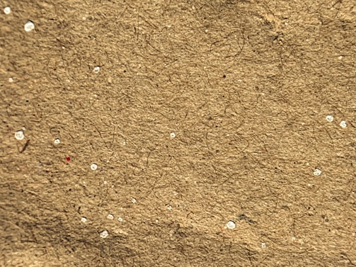 Close-up showing the fibrous texture of recycled paper sheets with natural tones and fibers visible.