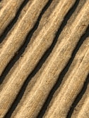 Close-up view of corrugated cardboard with parallel ridges and a textured surface in an earthy beige color.