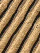 Close-up view of corrugated cardboard with parallel ridges and a textured surface in an earthy beige color.