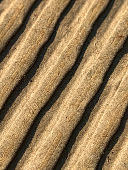 Close-up view of corrugated cardboard with parallel ridges and a textured surface in an earthy beige color.