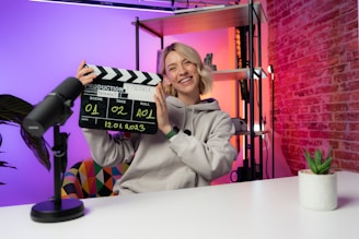 a woman holding a clapper in front of a brick wall
