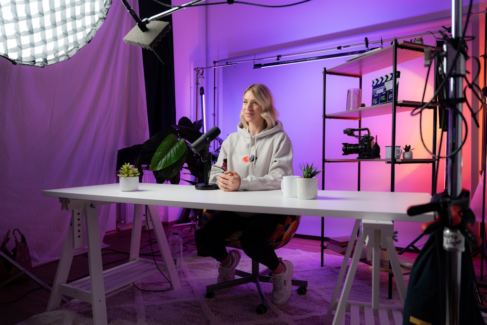 a woman sitting at a table in front of a camera