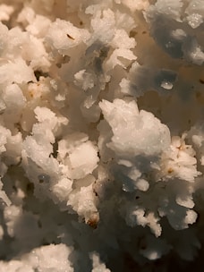 Close-up of shimmering white caustic soda flakes in a clean industrial container.