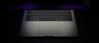 A laptop with a colorful backlit keyboard in a dim room.
