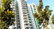 Modern apartment building exterior with balconies and greenery.