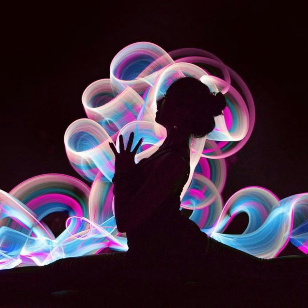 a silhouette of a person standing in front of colorful lights