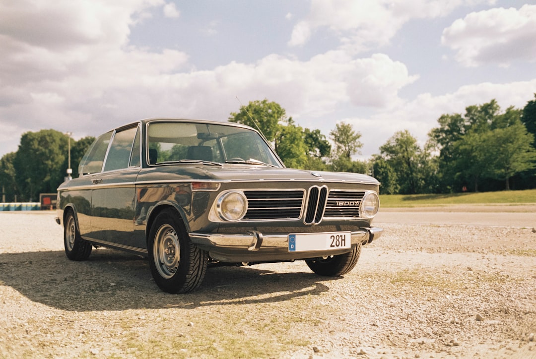 an old bmw is parked in a parking lot