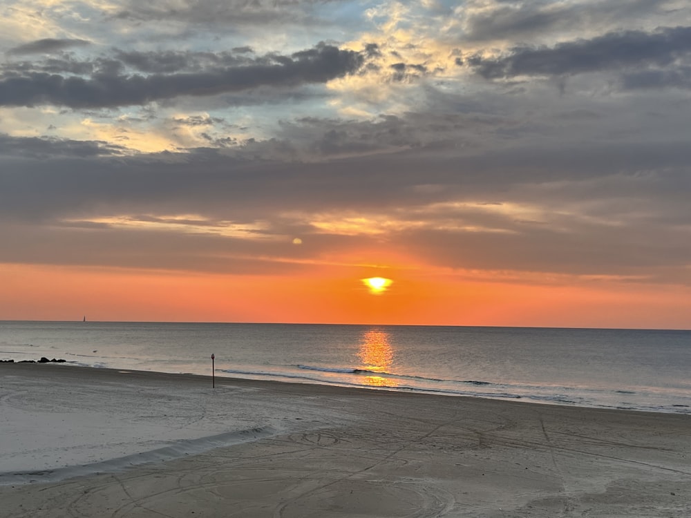 the sun is setting over the ocean on a cloudy day