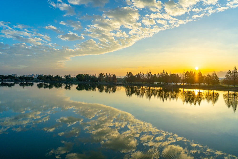 the sun is setting over a calm lake