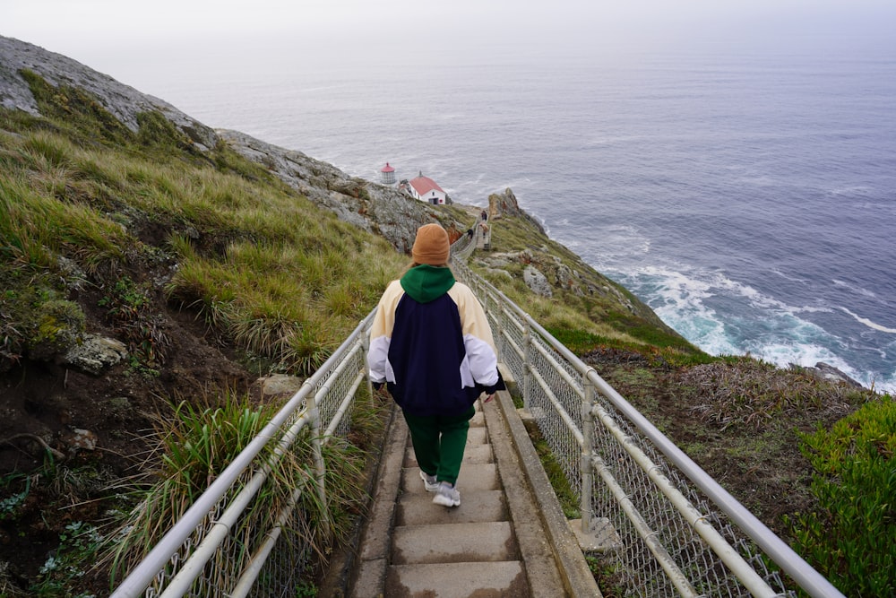 a person walking up a set of stairs next to the ocean