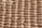 A close-up view of a honeycomb structure made from cardboard, featuring a repeating geometric pattern. The cells are hexagonal and crafted from a light brown paper material, giving a textured appearance with shadows that enhance the depth and structure.