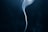 A smooth, delicate wisp of smoke rises gently against a dark background, creating a sense of movement and fluidity.