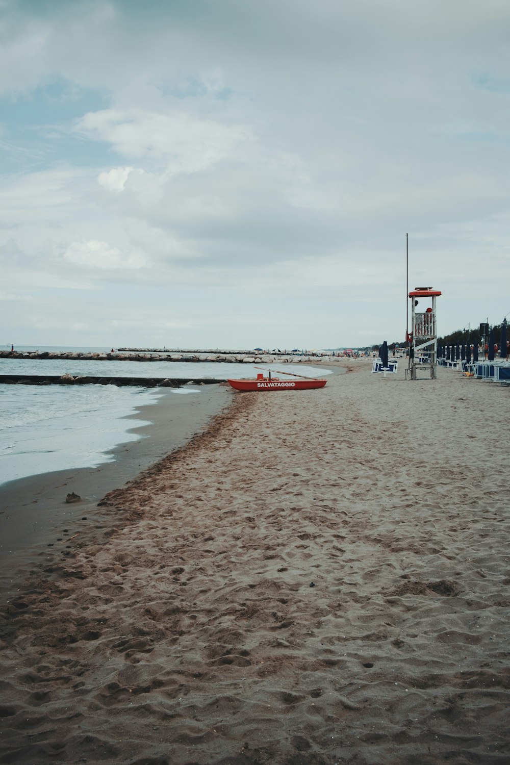 a red boat sitting on top of a sandy beach