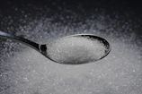 a spoon filled with sugar on top of a table