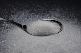 a spoon filled with sugar on top of a table