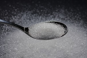 a spoon filled with sugar on top of a table