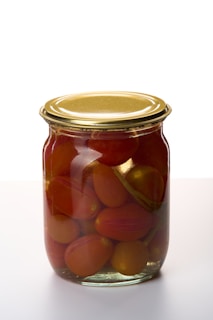 A vintage jar filled with vibrant red peeled tomatoes.