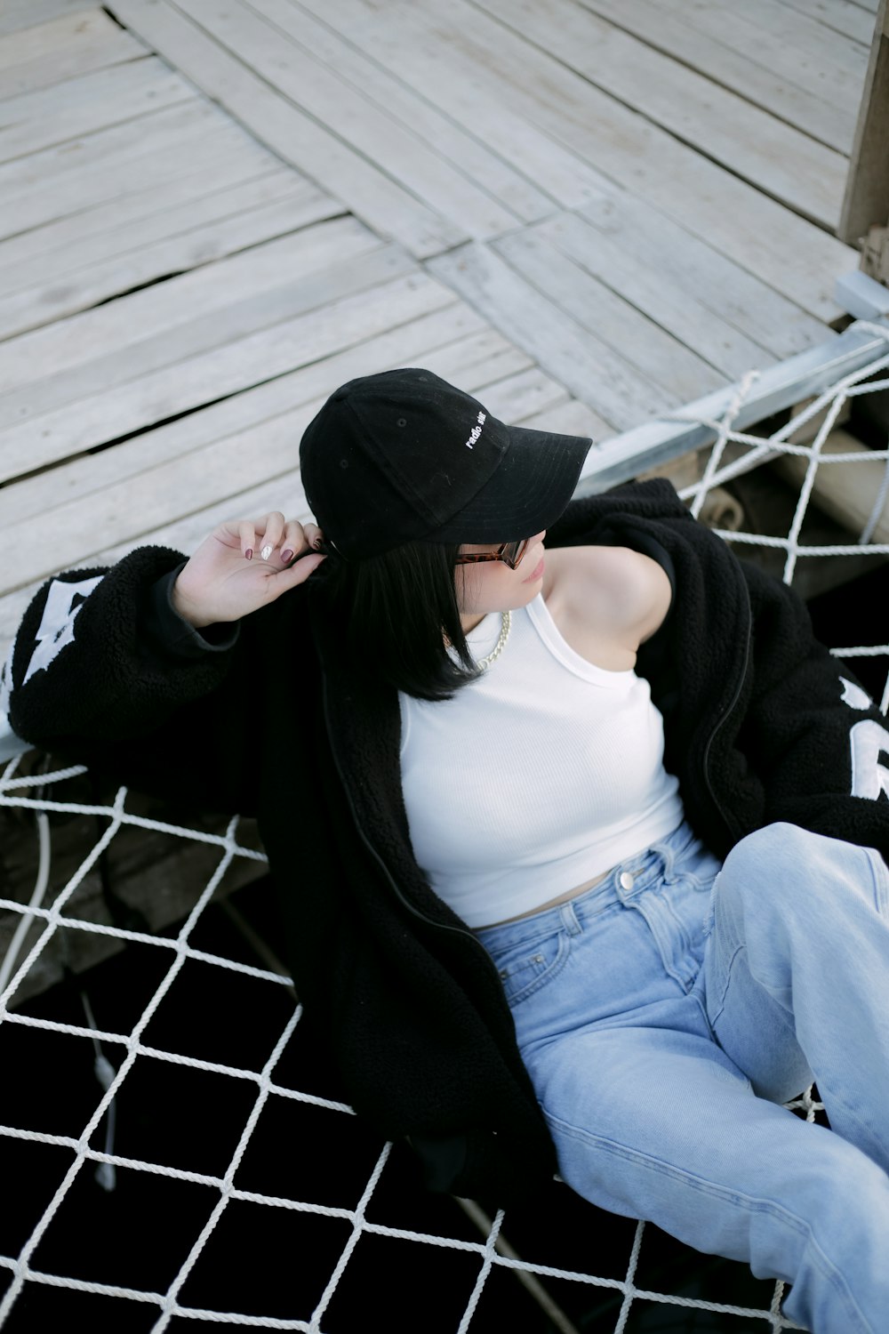 a woman sitting on the ground wearing a black hat