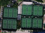 Wide angle view of the indoor tennis center showing multiple courts and seating area.