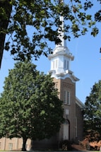 A welcoming church entrance with sunlight filtering through trees.